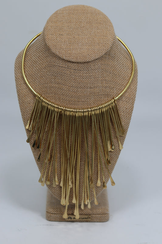 Handmade Kenyan brass choker necklace featuring a smooth rigid collar loaded with a dramatic, cascading fringe of individual brass rods, displayed on a burlap jewelry bust.