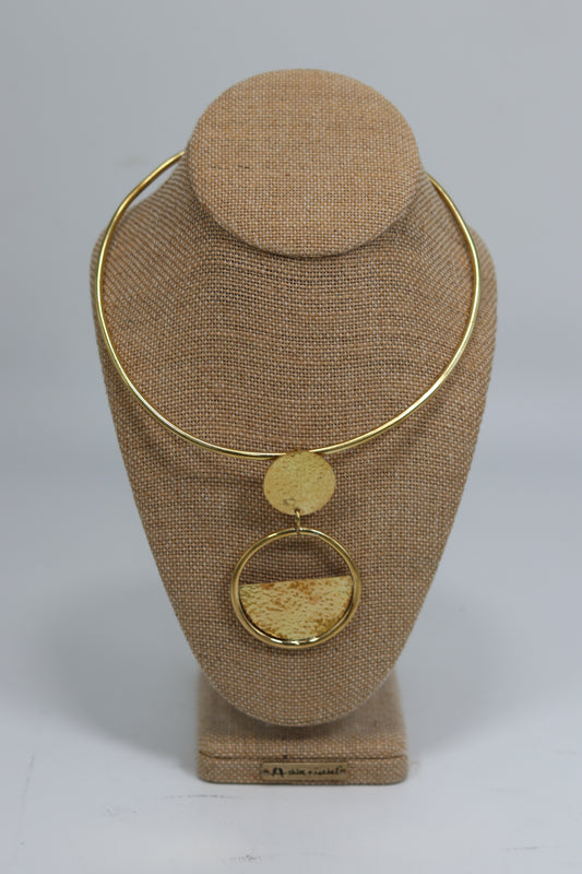 Handmade Kenyan brass choker necklace featuring a smooth rigid collar and a geometric double-disc pendant with a textured half-moon inlay, displayed on a burlap jewelry bust.